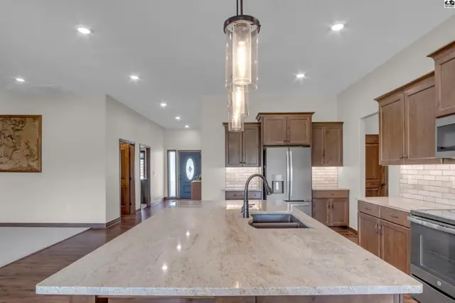 Spacious kitchen features a large island, granite countertops, and wood cabinetry.