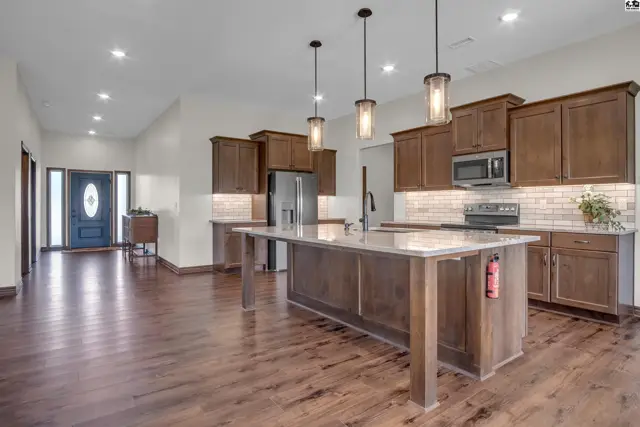 Spacious kitchen features a large island, granite countertops, and dark wood cabinetry.