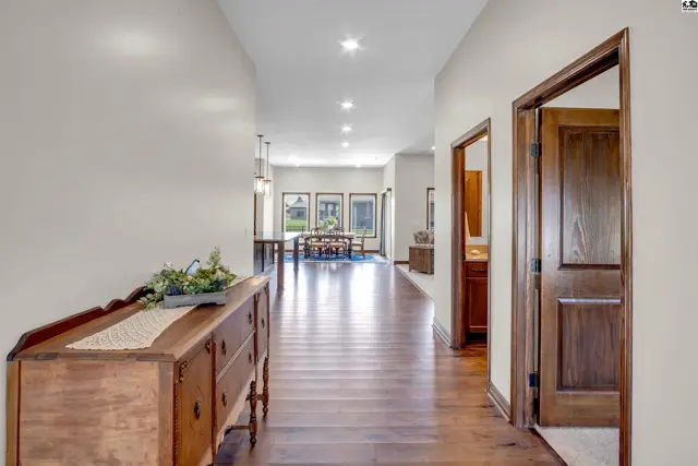 Spacious hallway with hardwood floors, recessed lighting, and a wooden dresser.