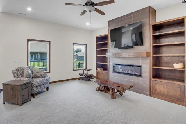 Spacious living room features a fireplace, built-in bookshelves, and a ceiling fan.