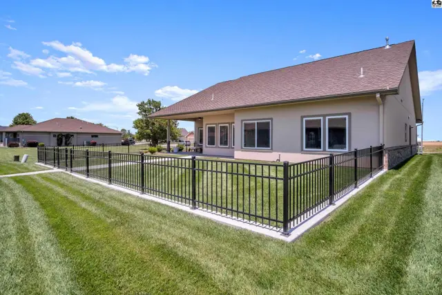 Fenced backyard with a covered patio adjacent to a stucco-sided home.