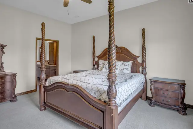 Spacious bedroom features a four-poster bed and carpeted flooring.