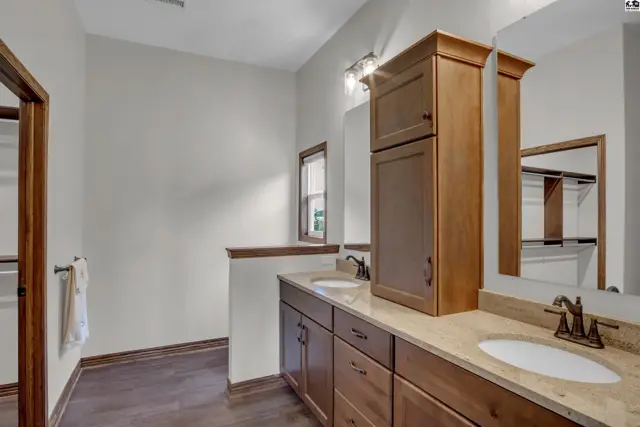 Spacious bathroom features a double vanity with granite countertops and ample wood cabinetry.