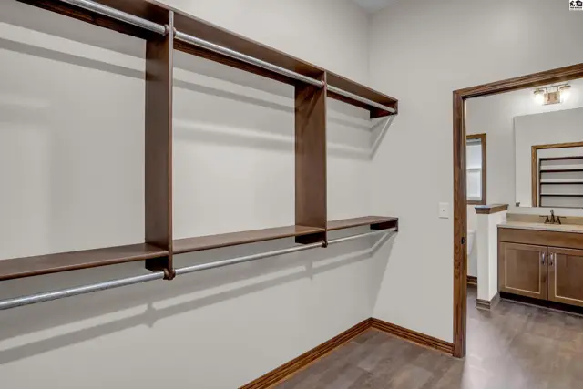 Spacious walk-in closet with dark wood shelving and hanging rods.