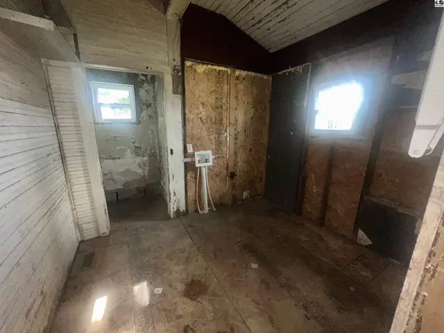 Interior view of a room with unfinished walls, exposed wood, and a small window.