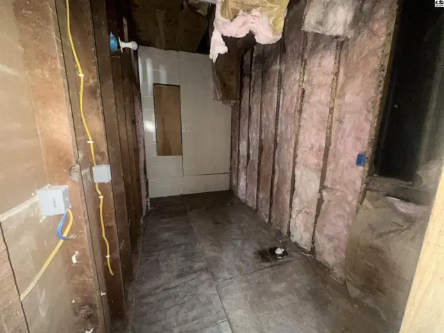 Unfinished room with exposed studs, pink insulation, and concrete floor.