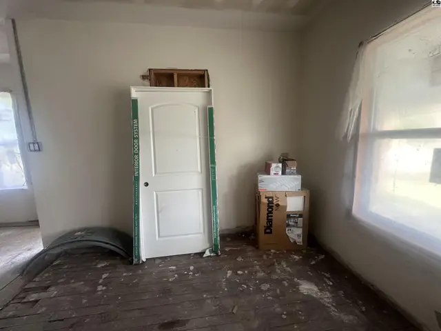Interior room with unfinished walls, a new white door, and construction materials.