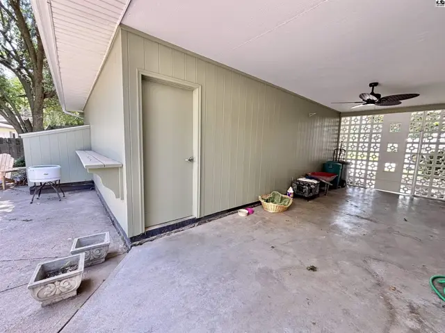 Covered patio with concrete floor, paneled walls, and decorative block windows.