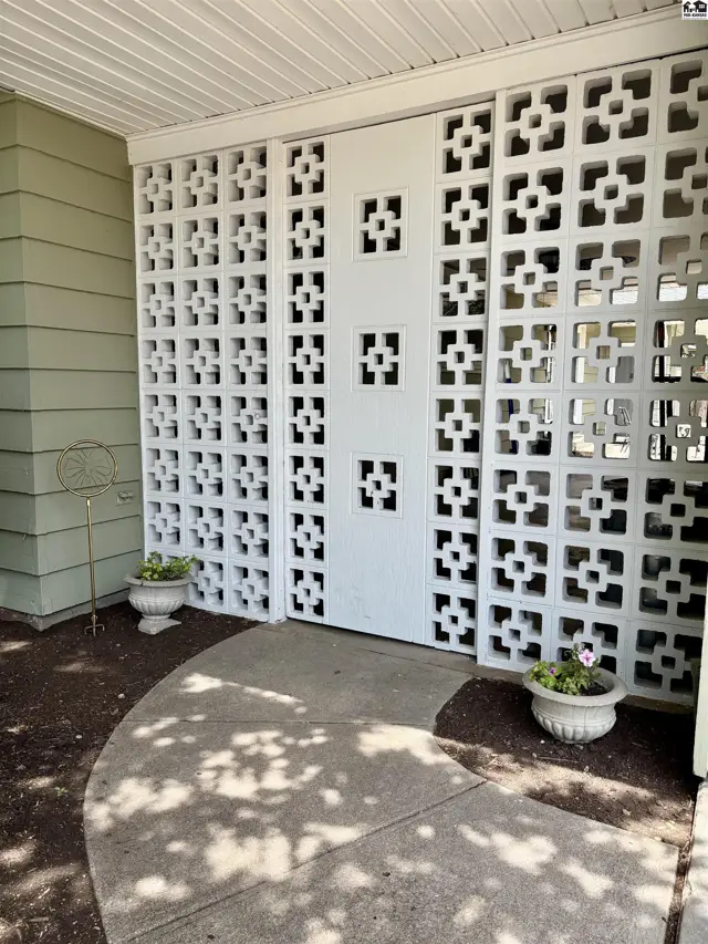 White decorative concrete blocks create a stylish screen and entryway with potted plants.