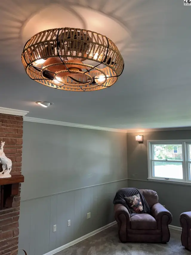 Living room with brick fireplace, plush armchair, and a unique woven ceiling fan.