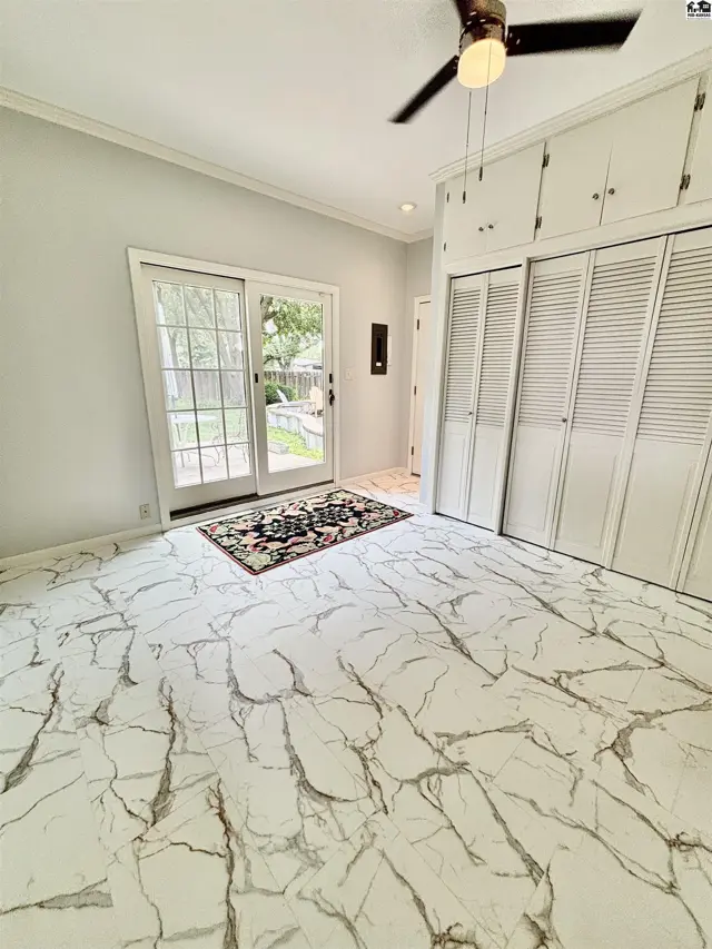 Spacious room with white marble-look flooring, sliding glass doors, and built-in white louvered closets.