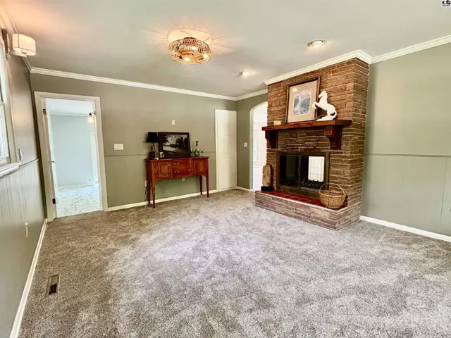 Living room features a large brick fireplace, plush carpet, and light green walls.
