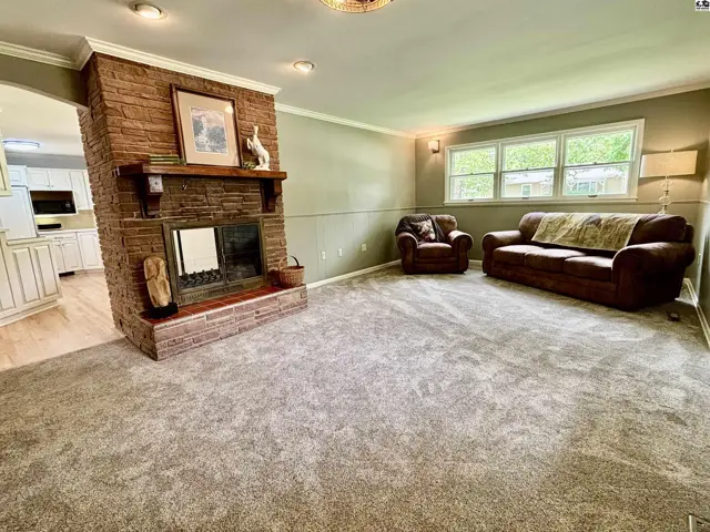 Living room with a rustic brick fireplace, plush carpet, and comfortable seating.