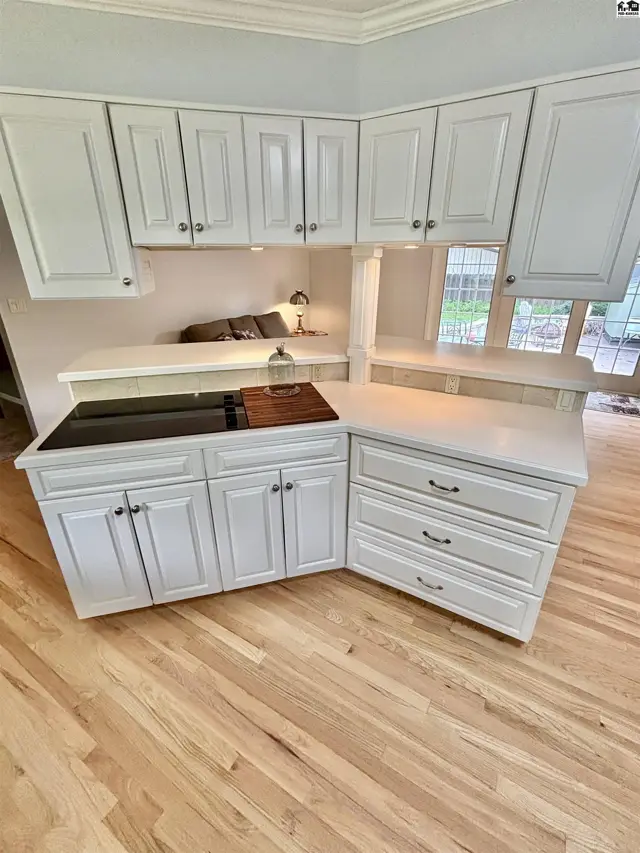 Bright kitchen with white cabinets, quartz countertops, and hardwood floors.