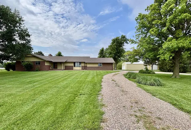 Spacious ranch home with brick and yellow siding, surrounded by lush green lawn and mature trees.