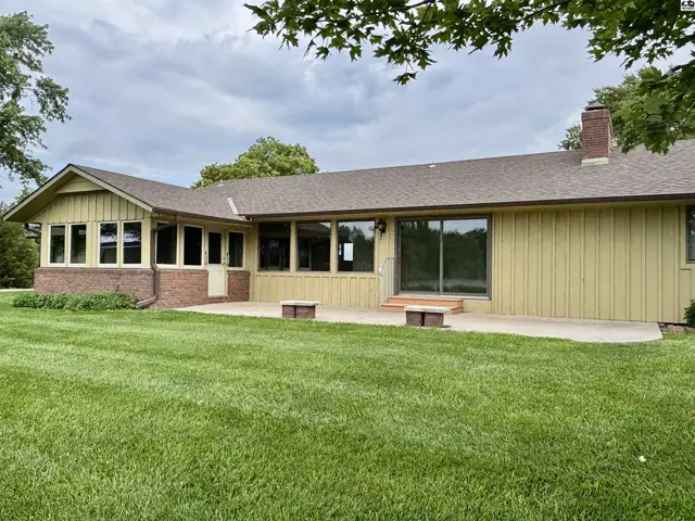 Spacious backyard patio with large windows and a brick accent wall on a light yellow home.