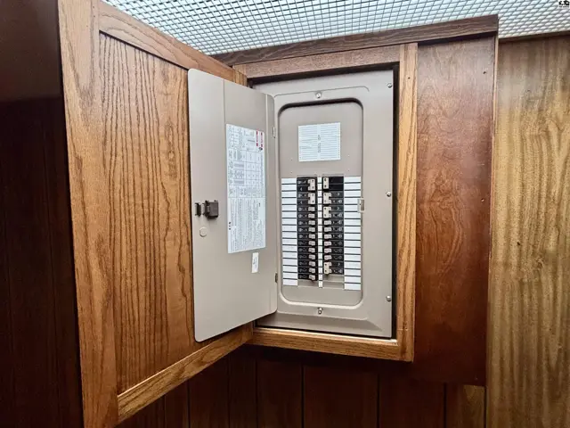 Electrical panel with breakers housed in a custom oak wood cabinet.
