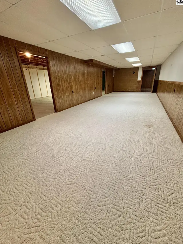 Spacious finished basement with textured carpet, wood-paneled walls, and recessed lighting.