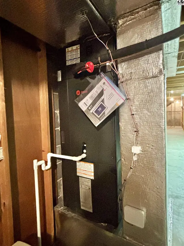 Furnace and ductwork with wood paneling and insulated walls in a utility area.