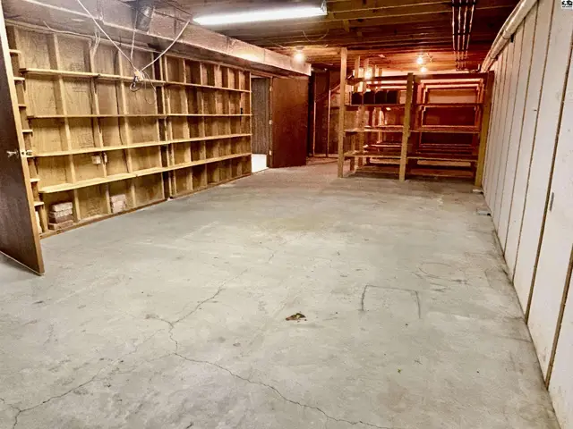 Spacious unfinished basement with extensive wooden shelving and concrete floors.