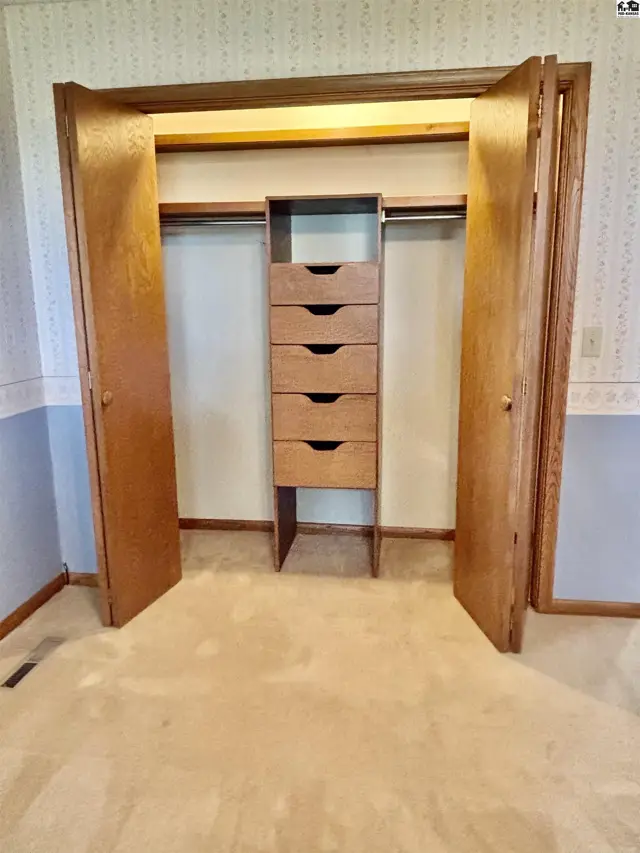 Spacious walk-in closet with wood doors, built-in drawers, and ample hanging space.