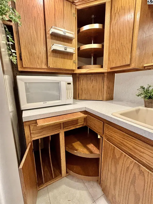 Corner kitchen cabinets with oak finish, a microwave, and built-in lazy Susans.