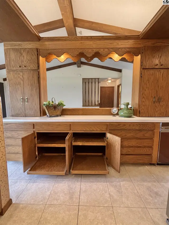 Oak cabinetry with open shelves and a scalloped wood valance above a long countertop.
