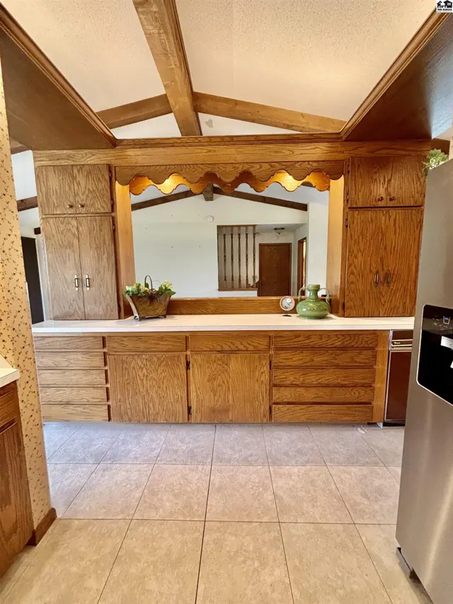 Spacious kitchen with light oak cabinetry, white countertops, and beamed ceiling.