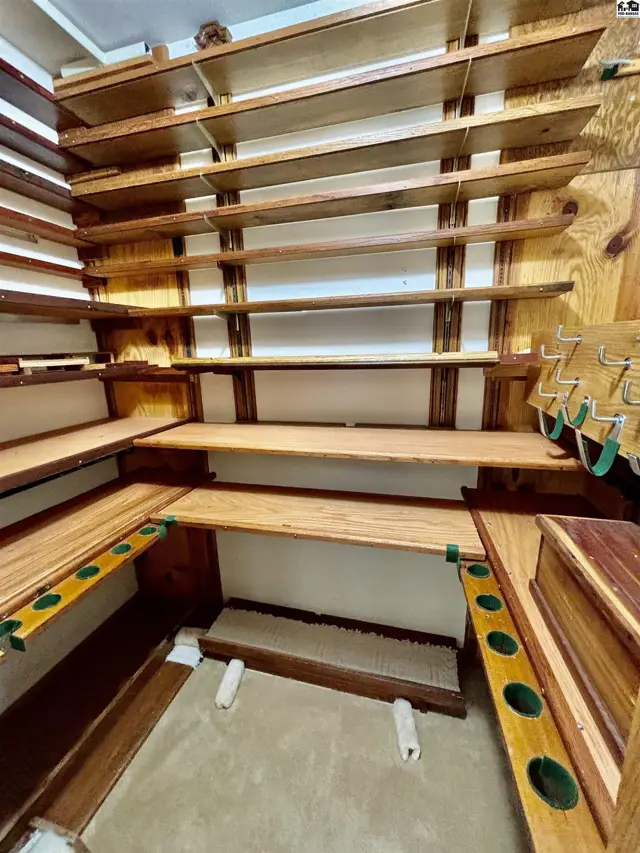 Corner pantry with extensive natural wood shelving and green accents.