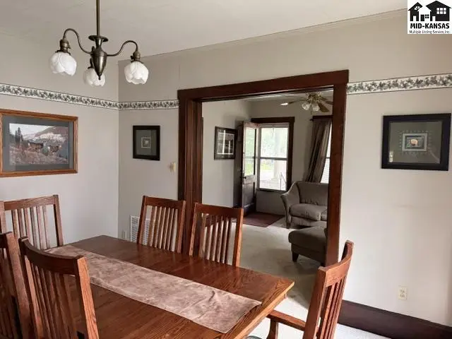 Dining room with a wooden table and chairs, opening to a living area with a sofa.