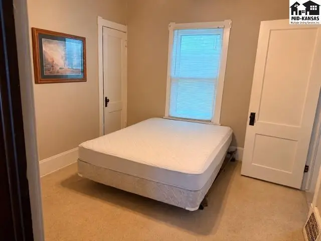 Bedroom with a mattress on the floor, a framed picture, and white paneled doors.