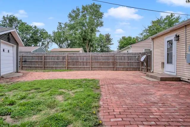 Spacious backyard with a brick patio, grass, and a wooden fence.