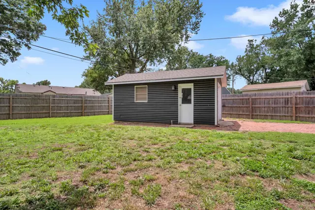 Dark gray corrugated metal siding on a detached garage with a white door and window.