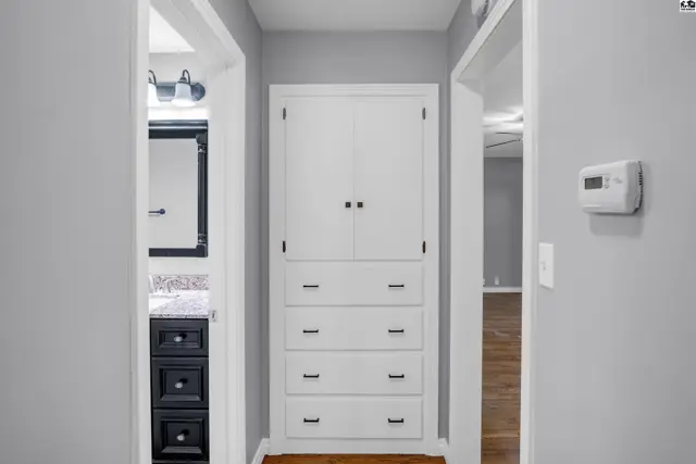 Hallway with built-in white cabinetry and a glimpse of a modern bathroom vanity.