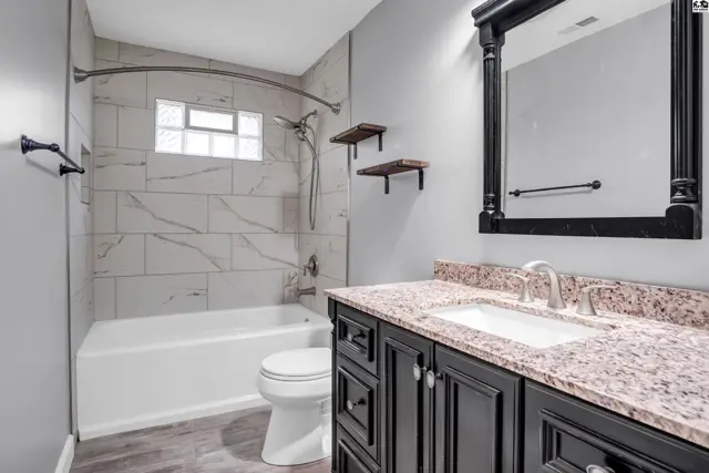 Modern bathroom with marble tile shower, granite vanity, and dark wood cabinetry.