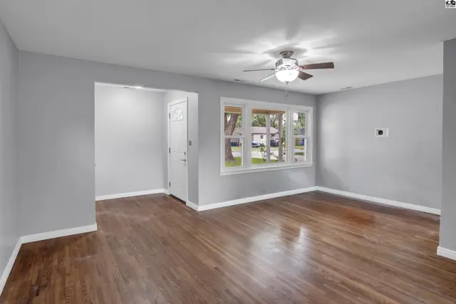 Spacious living room with hardwood floors, neutral gray walls, and a ceiling fan.