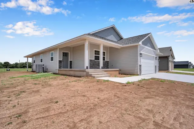 Modern gray siding home with stone accents, a covered porch, and a two-car garage.