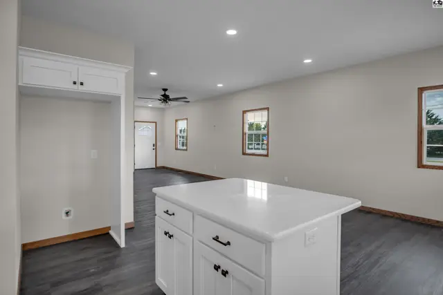 Modern kitchen island with white cabinetry and quartz countertop opens to a spacious living area.