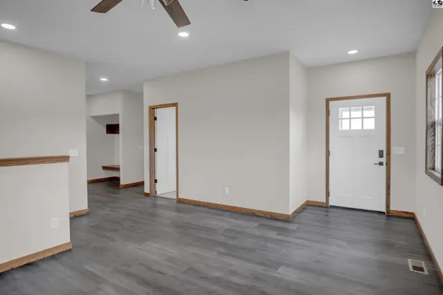 Spacious living area with dark wood-look flooring, white doors, and neutral walls.