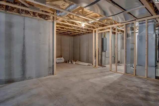 Unfinished basement with concrete walls and floor, framed for future rooms, and exposed ductwork.