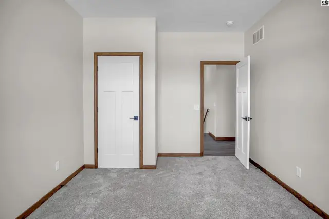 Neutral carpeted room with two white doors featuring wood trim and brushed nickel hardware.