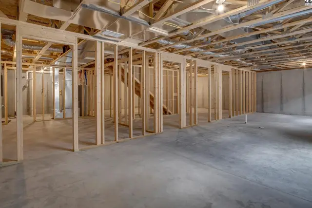 Unfinished basement with concrete floors, exposed wooden framing, and ceiling joists.