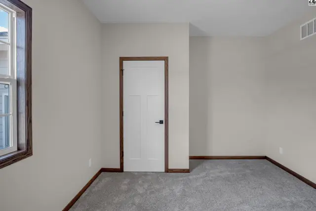 Neutral bedroom with plush gray carpet, white paneled door, and dark wood trim.