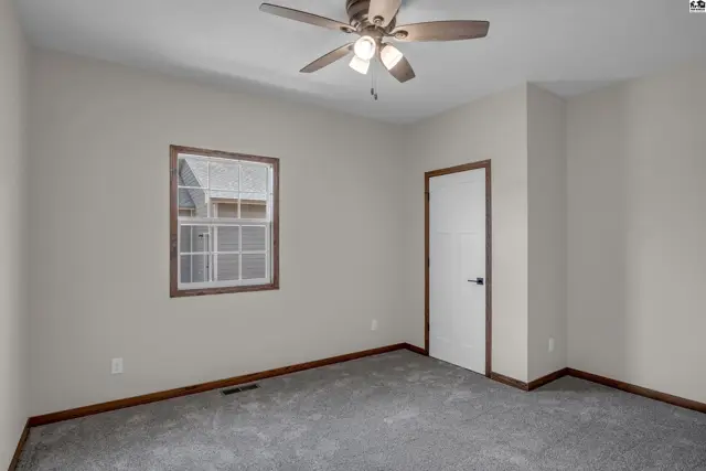 Neutral bedroom with gray carpet, white door, and wood trim.
