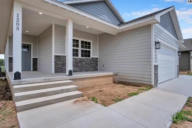 Modern home exterior with light gray siding, stone accents, and a covered porch.