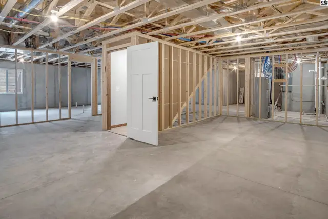 Unfinished basement with concrete floors, exposed joists, and framed walls awaiting completion.