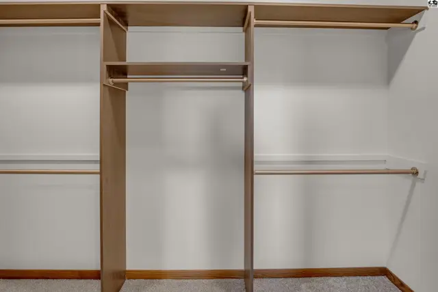Spacious walk-in closet with built-in shelving and multiple hanging rods.