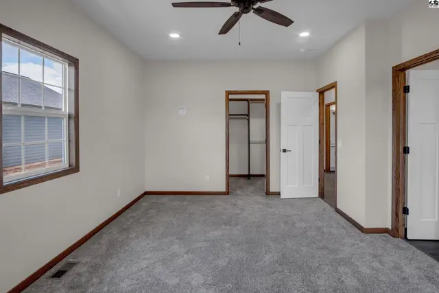 Spacious bedroom with plush gray carpet, white doors, and dark wood trim.
