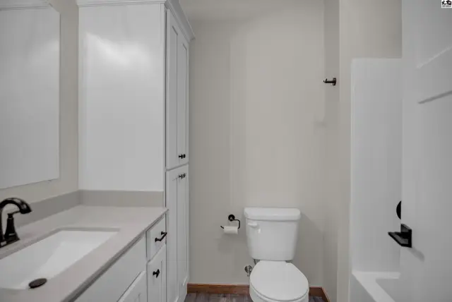 Modern bathroom with white vanity, quartz countertop, and a white toilet.