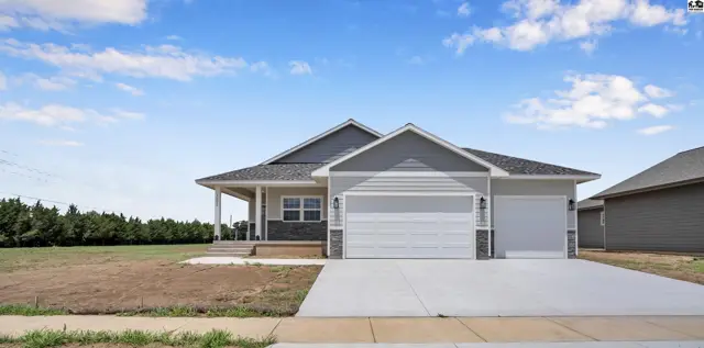 Modern ranch home features gray siding, stone accents, and a spacious three-car garage.
